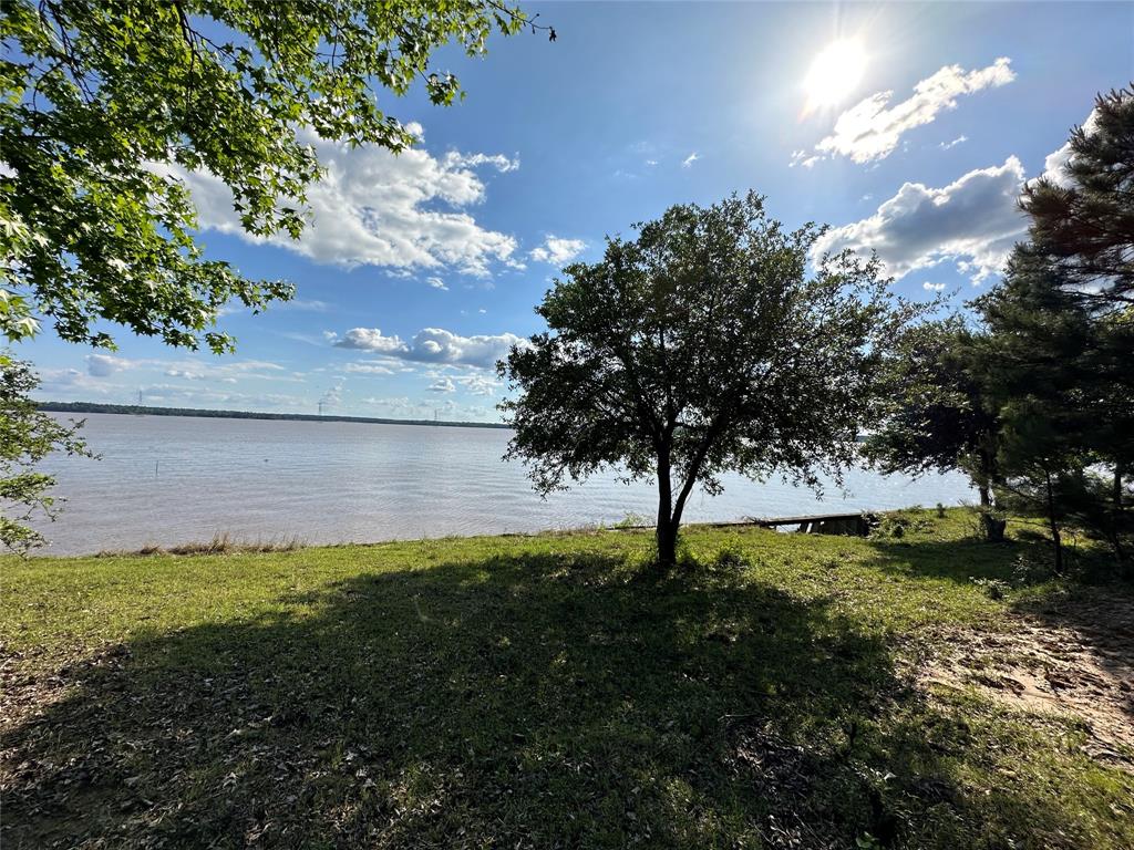 78+ acres, 1,200 ft. of waterfront on Lake Livingston. Beautiful ranch on Harts Creek Rd., near Carlisle in Trinity County. Land consists of: 8.9 acre of waterfront on the main body of the lake with over 1,200 ft. of waterfront with vinyl bulkhead. Nice high elevation that gently rolls down to the lake. Recreation boating, swimming, and fishing. 60’ X 40’ metal building with slab and 10’ x 40’ porch with a view. Utilities include city water, electric and septic. 68.5 acres, waterview with 4 gated entrances. 2,500 ft. of hard top road frontage on Harts Creek Rd. 50% hardwood and mature tall pine timber in production and 50% grazing pasture. Nice trails cut through the woods for hiking, biking or horseback. Excellent hunting. 0.6 acre tract with a sturdy scenic bridge connecting the two larger tracts of land. All sections of land are fenced, cross fenced and gated. Land is set up for low maintenance and family fun ready. Grass is planted, land cleared, water pipes are installed.