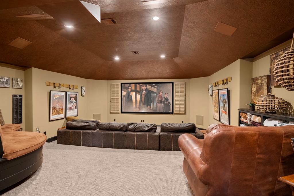Media room with tiered seating and projection style theater. Wet bar and snack station located outside the double doors.