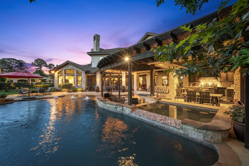 View from rock-slide formation of pergola, sunken fire pit and hot tub with built in underwater bar stools.