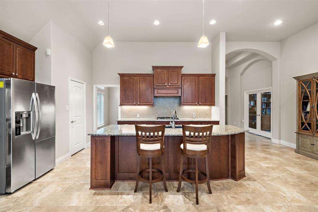 The eat-in kitchen boasts stainless steel appliances, under-cabinet lighting, a walk-in pantry, access to the dining area, and a granite island with counter seating. Find double doors that lead to the adjacent study/home office.