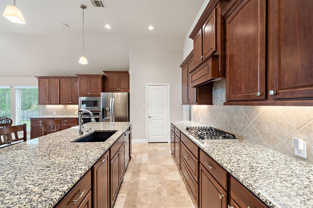 Tasteful and functional, this modern kitchen boasts granite countertops, stainless steel appliances, a tile backsplash, a breakfast bar, and a long island with built-ins and counter seating. Enjoy great storage space courtesy of the walk-in pantry and multiple cabinets.