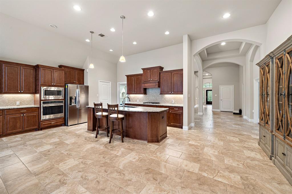 Effortlessly lead guests into the kitchen from the entryway, offering generous floor space, extensive countertops, a breakfast bar, and a large island with counter seating.