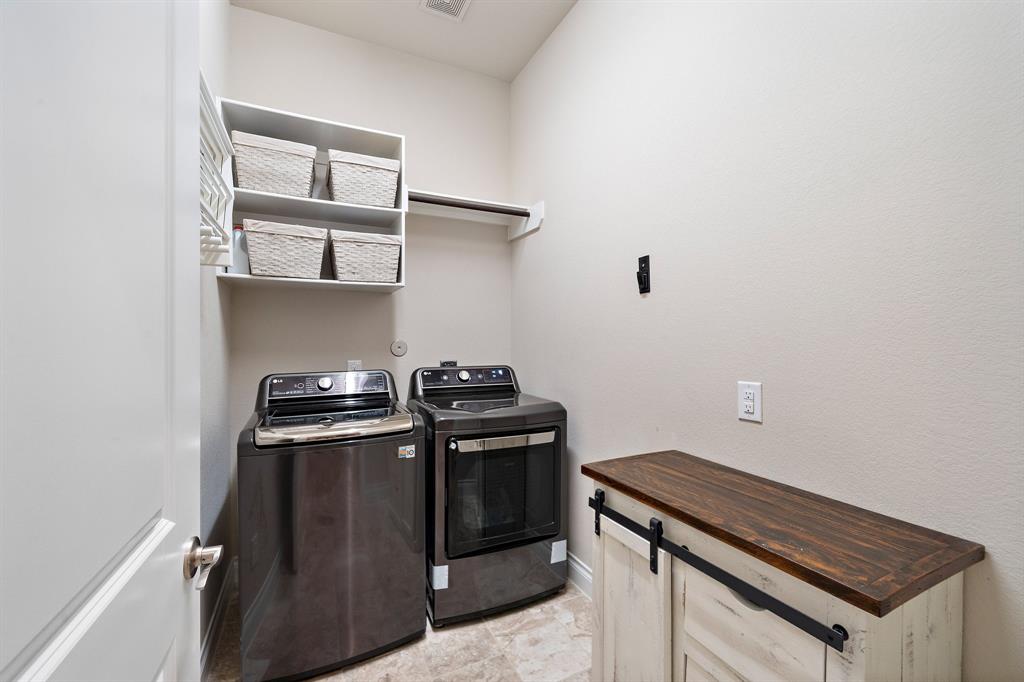 Located right off the entryway, the utility room features a hanging rack, built-ins, overhead shelves, and great space for a dryer and a washer.