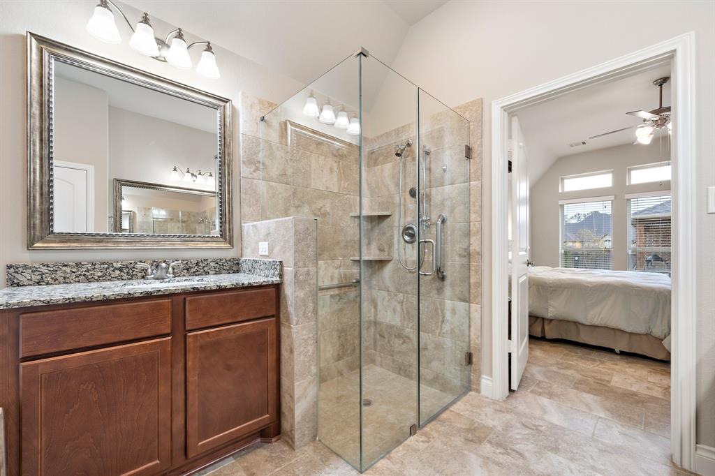 The ensuite bath comes complete with a walk-in shower fitted with sleek glass walls, dual shower heads, and a tile surround—conveniently located next to a vanity area.
