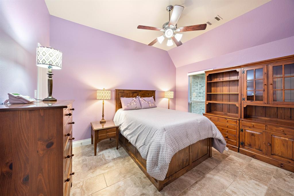 Ideal for a guest suite, this secondary bedroom showcases tile floors, a sloped ceiling, and great storage courtesy of the wooden cabinets and shelves.