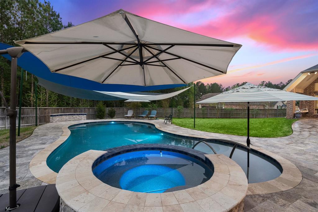 The in-ground swimming pool features an attached tub, elegant stonework, and nearby seating areas, making it an ideal spot to cool off!