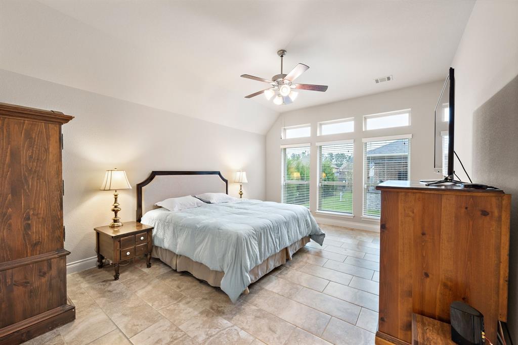 Retreat into the expansive primary suite boasting high vaulted ceilings, tile floors, and tall windows that usher natural light into the room.