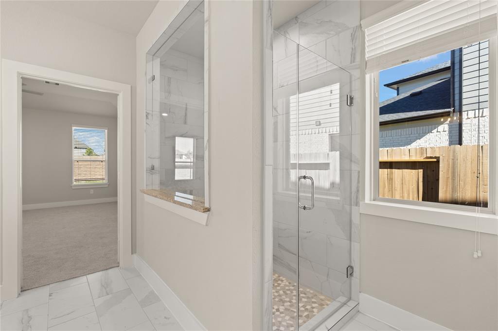 This additional view of the primary bath showcases the large walk-in shower with tile surround.