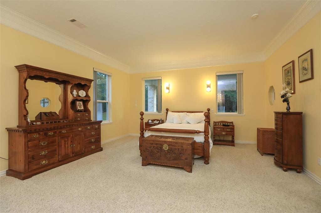 Huge Primary bedroom suite that features double crown molding, carpet, attractive wall sconces, and plenty of windows for natural light.