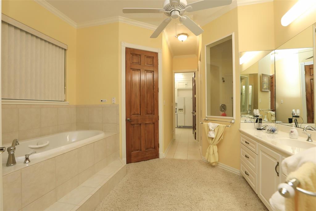 This primary bathroom has a soaking garden tub, walk in shower, marble vanity, and his and hers walk in closets.