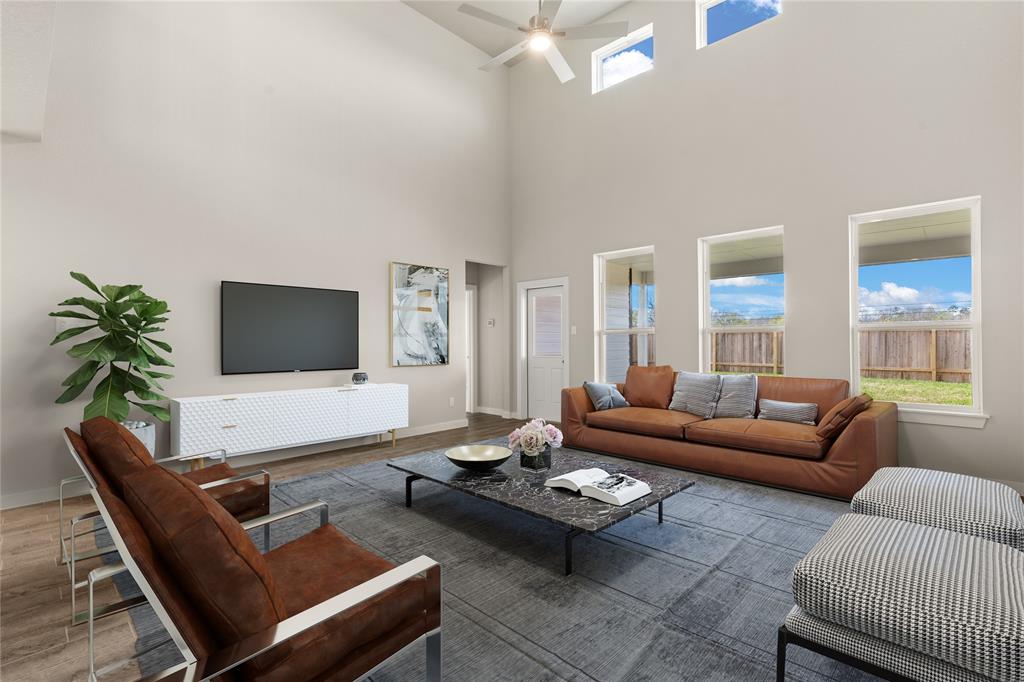 Gather the family and guests together in your lovely living room! Featuring soaring high ceilings, recessed lighting, dark stained ceiling fan, custom paint, gorgeous floors and large windows that provide plenty of natural lighting throughout the day.