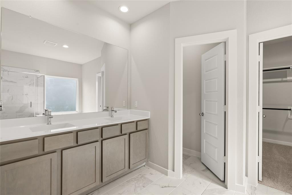 This primary bathroom is definitely move-in ready! Featuring light stained cabinets with light countertops, spacious walk-in closet with shelving, high ceilings, custom paint, sleek and dark modern finishes.