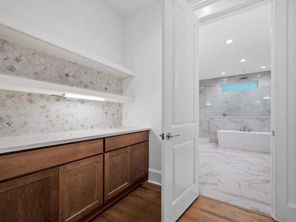 Enjoy your private coffee bar with marble backsplash & custom wood cabinets tucked away in the primary suite