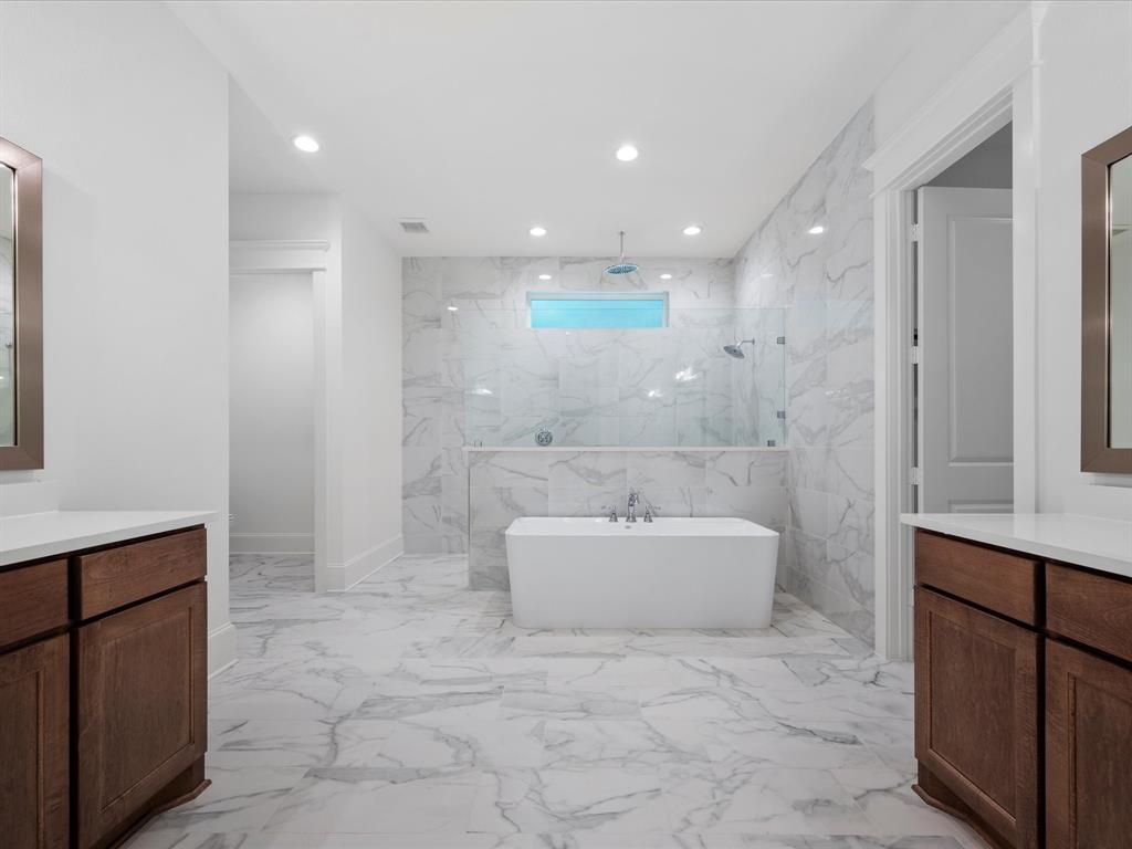 A spa-like primary bath with a soaking tub, separate walk-in double shower, and dual stained vanities with custom framed mirrors