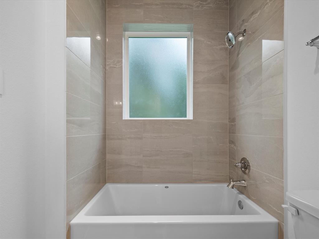 A tiled tub-shower shared by the secondary bedrooms