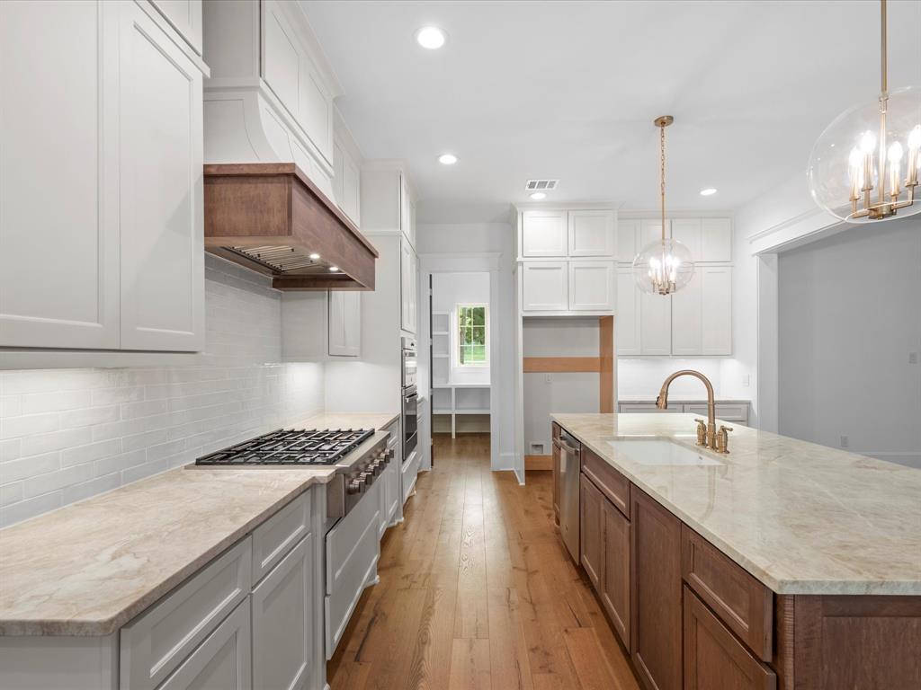 A 6-burner gas cooktop with custom vent hood, oversized single basin under mount sink and huge walk-in Chef\'s office pantry offering abundant storage and workspace!