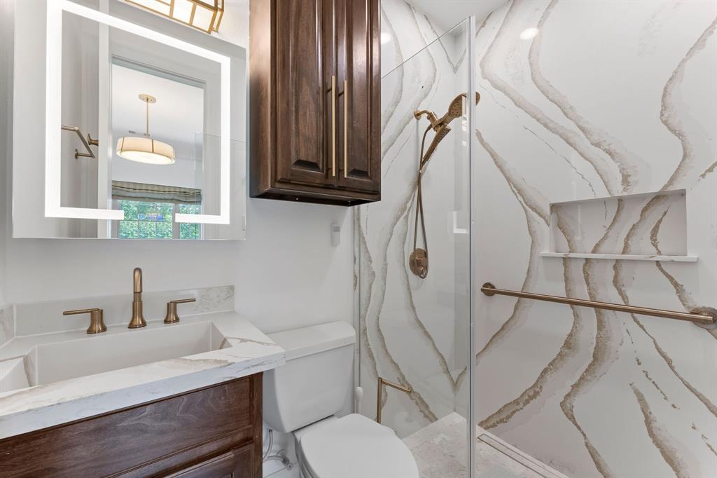 The en-suite bathroom in the office features a frameless anti-fog LED vanity mirror with front light.  The walk in shower is Venezia champagne gold quartz, oversized grip bar, linear drain in the floor, and the hardware is champagne gold.