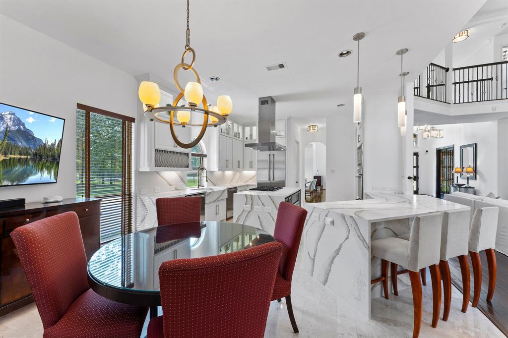 The breakfast area is located off the kitchen and provides a cozy gathering area for morning coffee. The breakfast room, kitchen, laundry room and pantry feature limestone floors. This view shows the gorgeous Venezia Gold Jumbo quartz waterfall countertops.