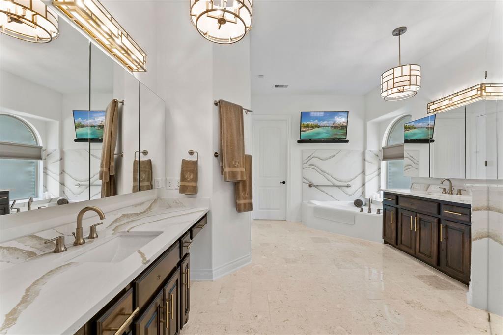 The Primary Owner's bathroom is truly reflective of the entire home with Venezia champagne quartz counters, champagne gold hardware, frameless triple medicine cabinet mirrors, designer upgraded lighting, a jet tub, separate walk in shower and access to the oversized closet.