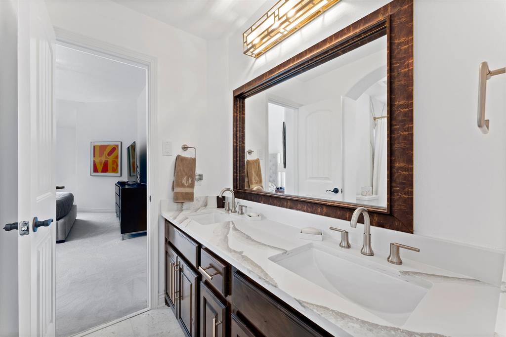 The Jack and Jill bathroom features quartz countertops, upgraded lighting, champagne gold hardware, and double sinks for convenience.