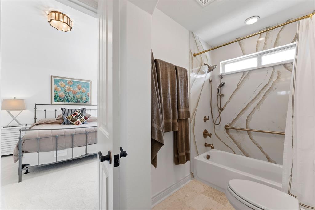 The shower in the Jack and Jill bathroom has Venizia champagne quartz walls, an oversized grip bar, and an upgraded shower head.