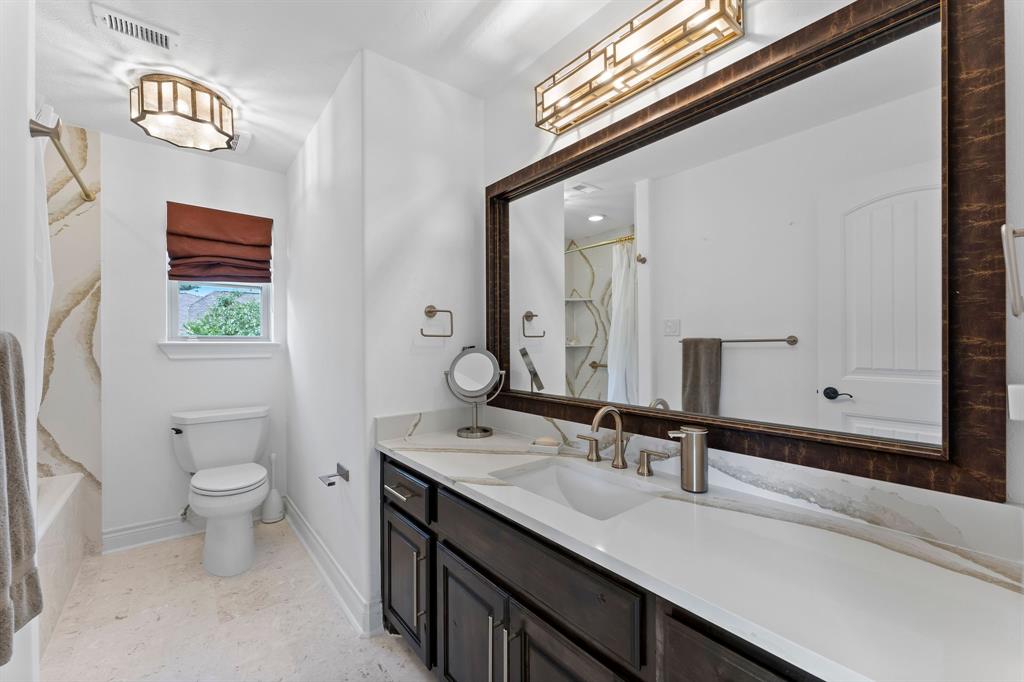 The en-suite bathroom for bedroom number 4 features Venezia champagne quartz counters and shower walls, champagne gold hardware, and designer light fixtures.