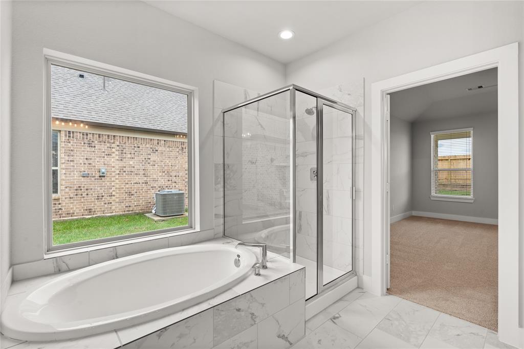 This additional view of the primary bath features a large walk-in shower with tile surround and a separate garden tub perfect for soaking after a long day.