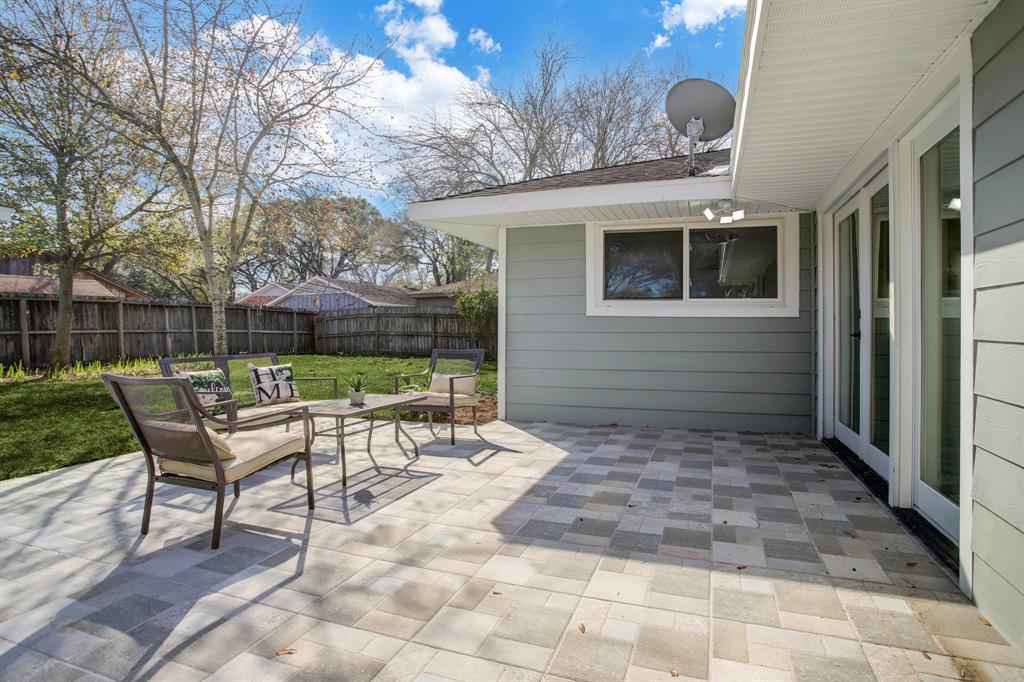Large, tiled patio space in tree-shaded back yard, connected by french doors to family room