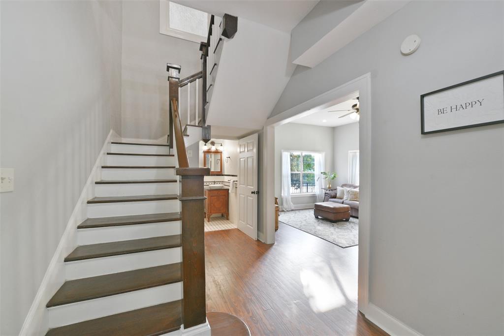A split staircase with richly stained wood treads and handrails extends up from the foyer to a second-floor landing that branches off into three bedrooms, one bathroom, and a centrally located flex-use game room or fourth bedroom.
