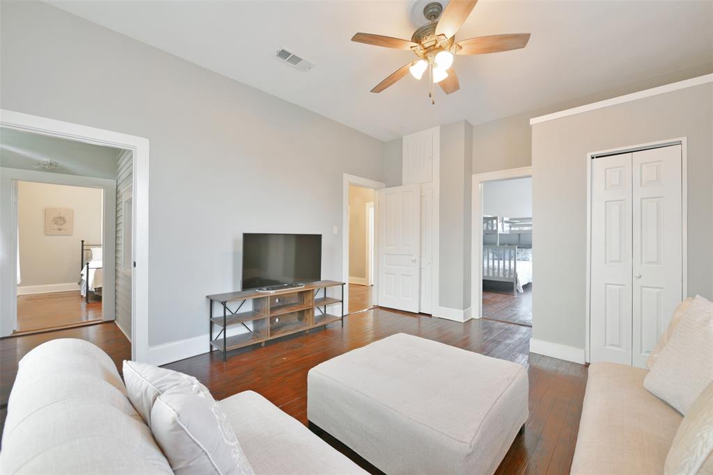 From the second-floor landing, enter this flexible-use space to find elevated ceilings with a lighted ceiling fan, neutral paint, handsome wood floors, a bi-fold door closet, and a pair of sunlit windows with gauzy draperies.