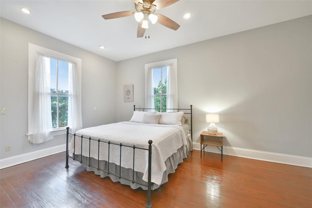 The largest of the three bedrooms measures 18\'x13\' and features recessed lighting in addition to a lighted ceiling fan, neutral paint with oversized baseboards, wood floors, and a pair of windows.