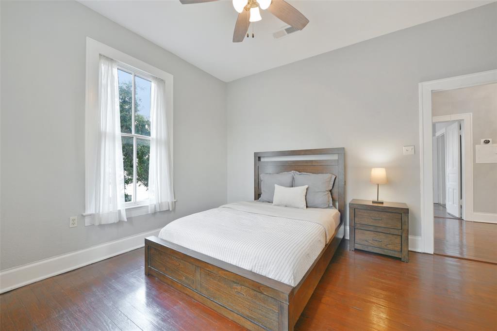 This bedroom measures approximately 13\'x12\' and offers all of the same features as the previous rooms, including wood floors, a lighted ceiling fan, neutral paint, and a window with gauzy white draperies.