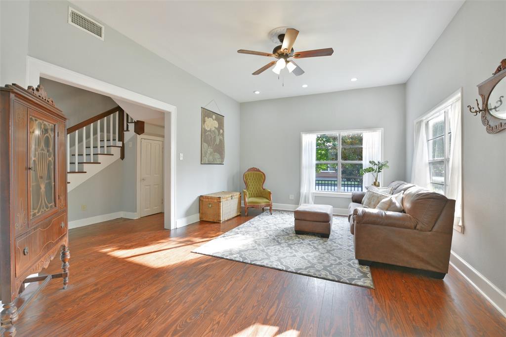An alternate view of the family room highlights the light and bright space and a wide entrance leading to the foyer, the staircase with a large storage space beneath it, and a full bathroom located on the first floor.