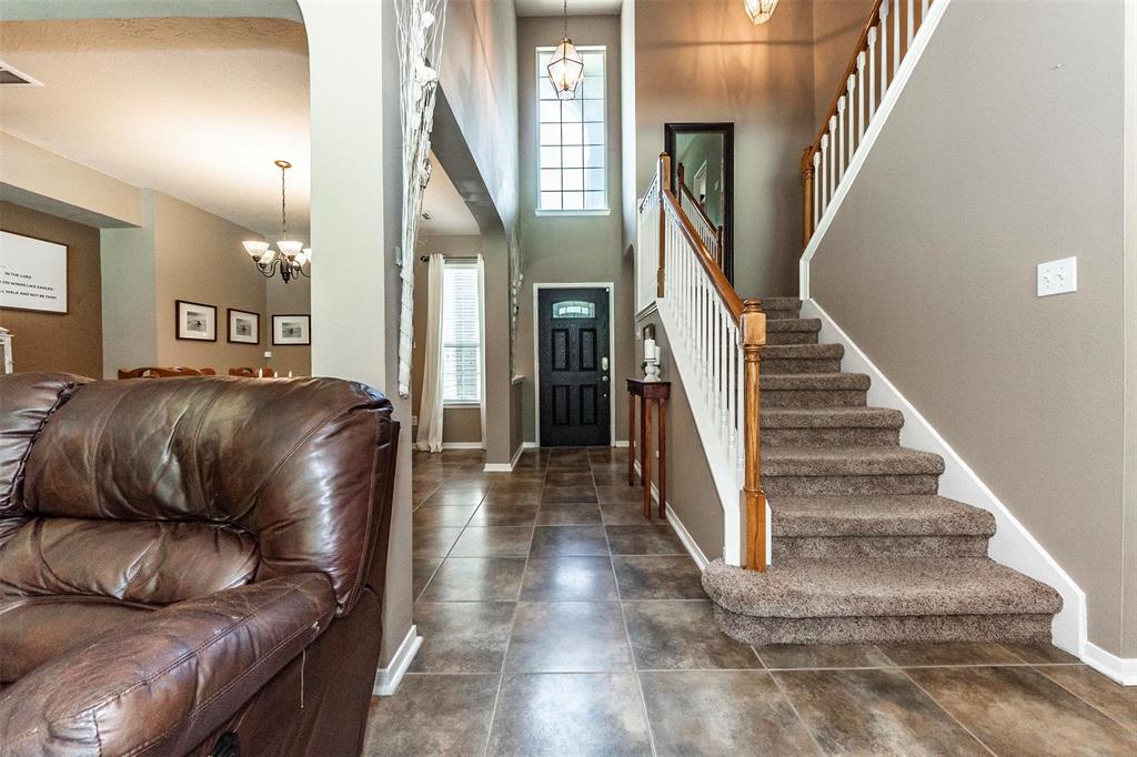 Two-story entrance to with stylish tile flooring, high ceilings, and staircase.
