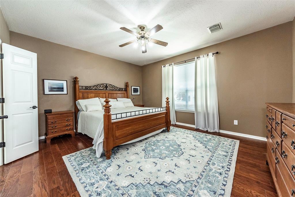 Spacious primary bedroom downstairs with stunning wood floors and backyard views.