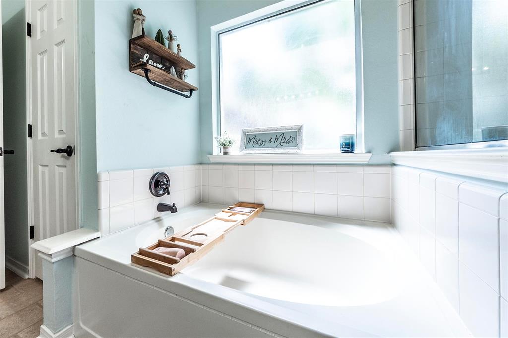 Spacious spa-like soaking tub in the primary bath with great natural lighting and privacy glass window.