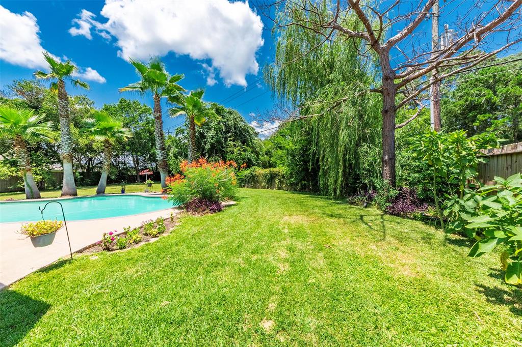 Beautiful trees, plants, shrubs and flowers surround the pool and large backyard.