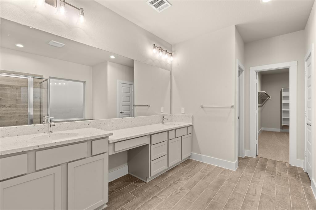 This primary bathroom is definitely move-in ready! Featuring light stained cabinets with light countertops, spacious walk-in closet with shelving, high ceilings, custom paint, sleek and dark modern finishes.