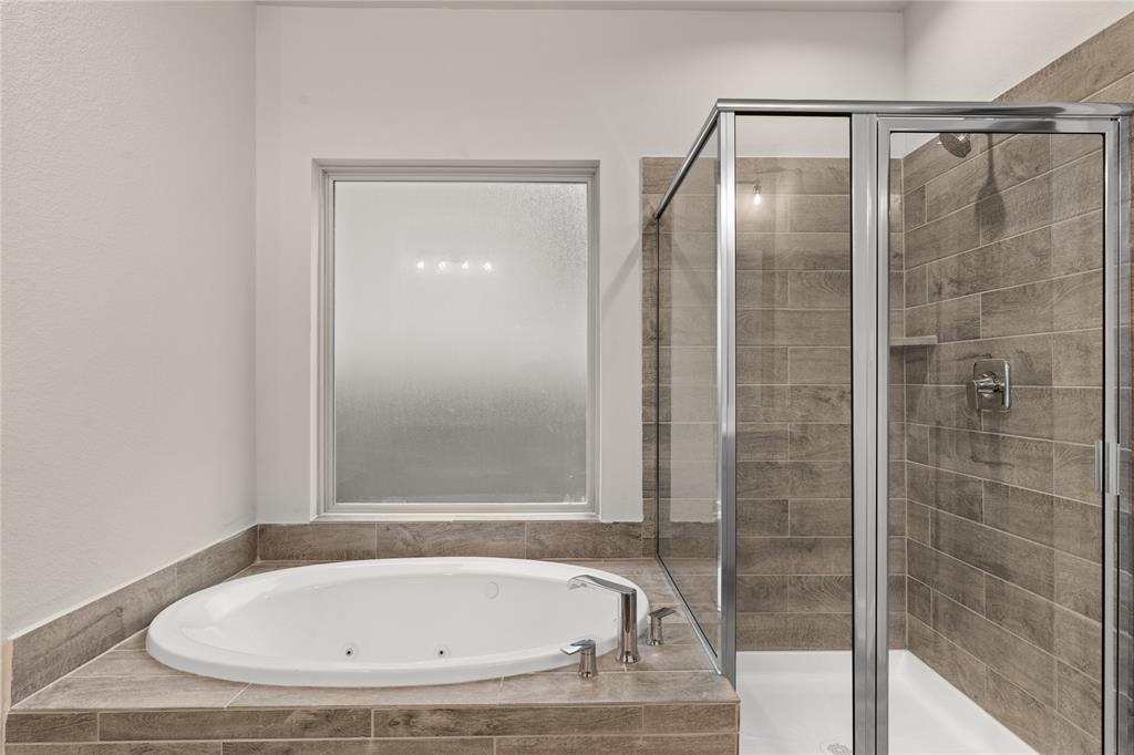This additional view of the primary bath showcases the walk-in shower with tile surround and a separate garden tub perfect for soaking after a long day.
