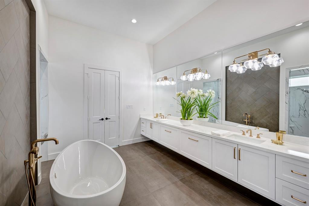 Step through double doors into this serene primary bath. A sculptural soaking tub is framed with classic herringbone patterned tile. Un-lacquered Brizo brass fixtures and hardware add warmth and richness.