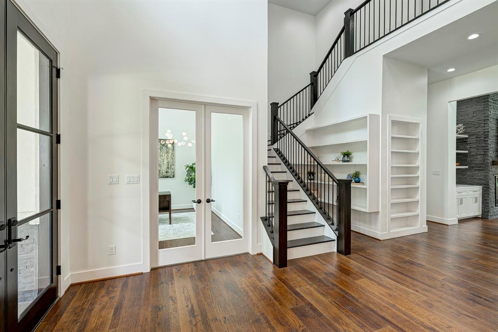 Step inside to a two-story foyer clad in hand-scraped wood floors and display shelves. The sleek staircase carries your eye up to twin chandeliers.