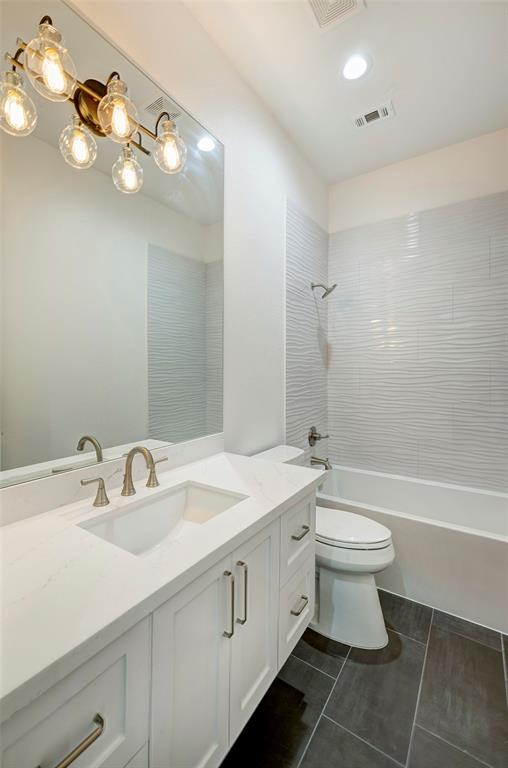 One of five secondary bathrooms, each with quartz countertop, modern lighting, and dynamic shower wall tile for added interest.