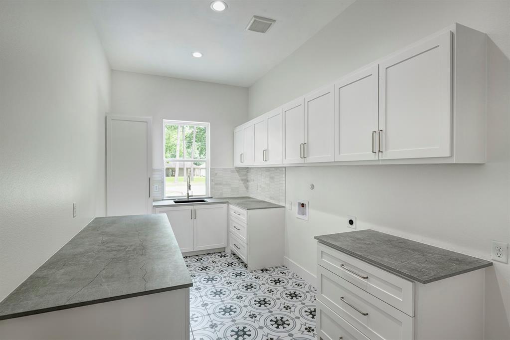 You\'ve never seen a laundry room like this! Hard working and stunning Dekton countertops, marble backsplash, sink, broom closet, and space for a secondary refrigerator. Window overlooks the motor court.