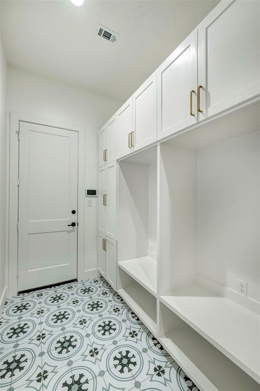 Connected to the three bay garage is the mud area with lockers and shoe storage. A patterned tile adds visual interest underfoot. Laundry is accessed to the left, and the oversized single bay garage is across the hall.