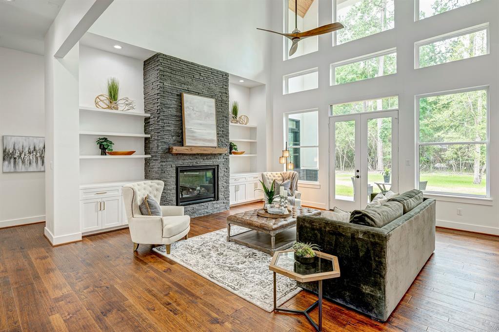 The stacked stone clad fireplace is flanked by display shelves and lower storage. Hallway beyond leads to the primary suite.