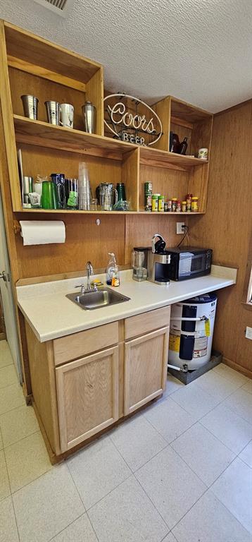 This is the small kitchenette space with a sink, microwave, coffee maker, and bar area. Small water heater tucked under the counter.