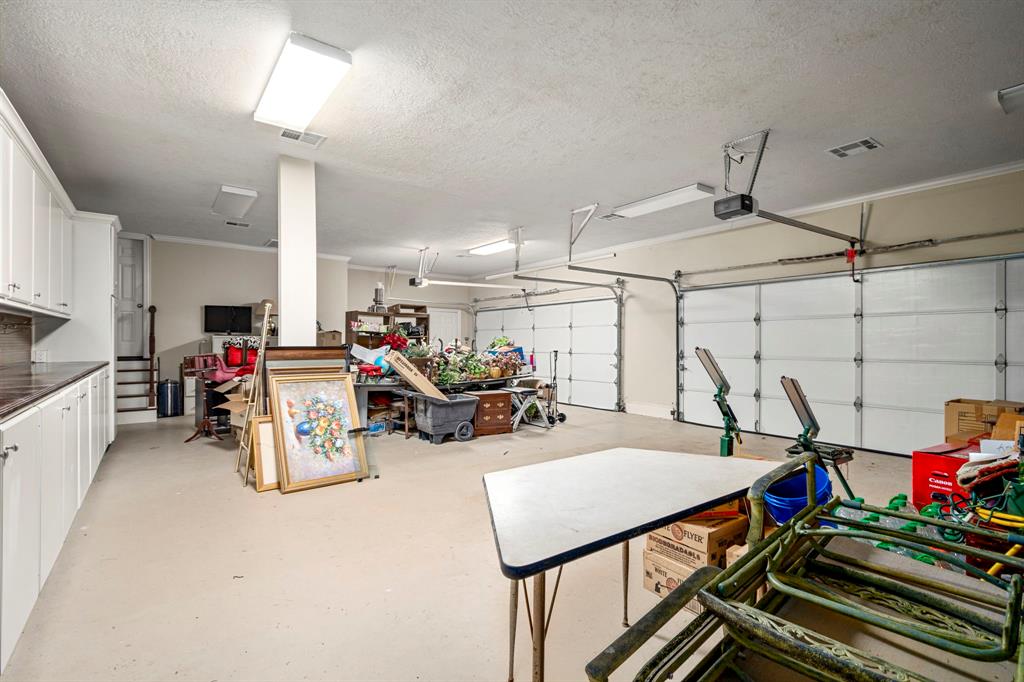 This 4 car garage/workshop is a dream for car projects and to protect valuable tools in the long and spacious workbench to the left. This garage/workshop is climate controlled for comfort.  Just outside the garage doors is a  porte cochere with an additional 4 car covered space. The door at the staircase goes to a cavernous walk up attic.