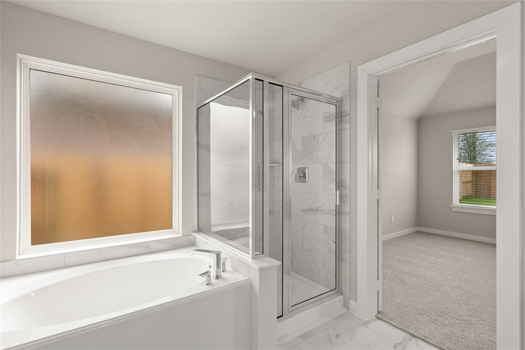 This additional view of the primary bath features a walk-in shower with tile surround and a separate garden tub perfect for soaking after a long day.