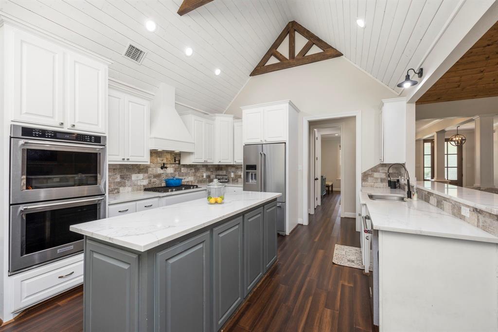 Step into this beautiful, modern kitchen. Cathedral ceilings and beautiful wood accents. The open kitchen is a chef\'s delight complete with plenty of quartz countertops, double ovens, gas cooktop with pot filler, large island. Custom tile backsplash provide a touch on warmth.