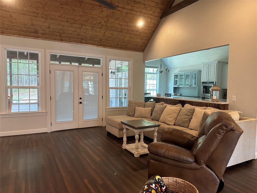 Spacious living room with gorgeous cathedral ceilings with wood accents. French doors open into the screened in porch with views of your wooded backyard.